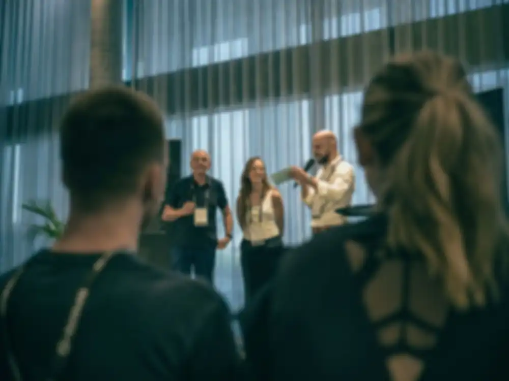 Three people stand on stage and talk about the project